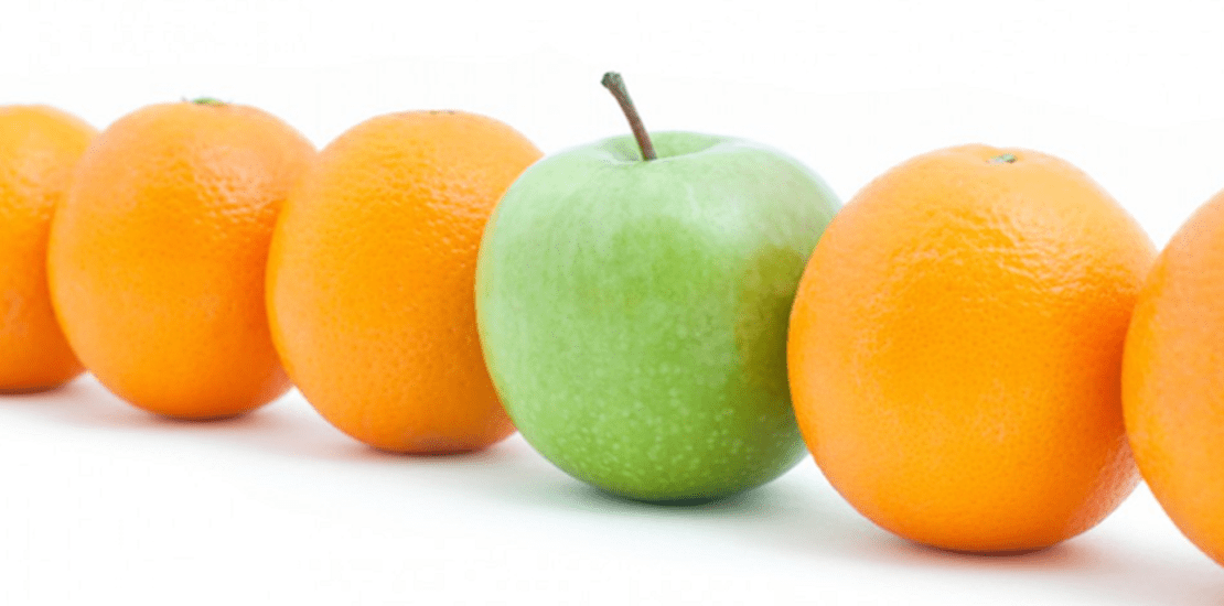 An array of oranges and a green apple