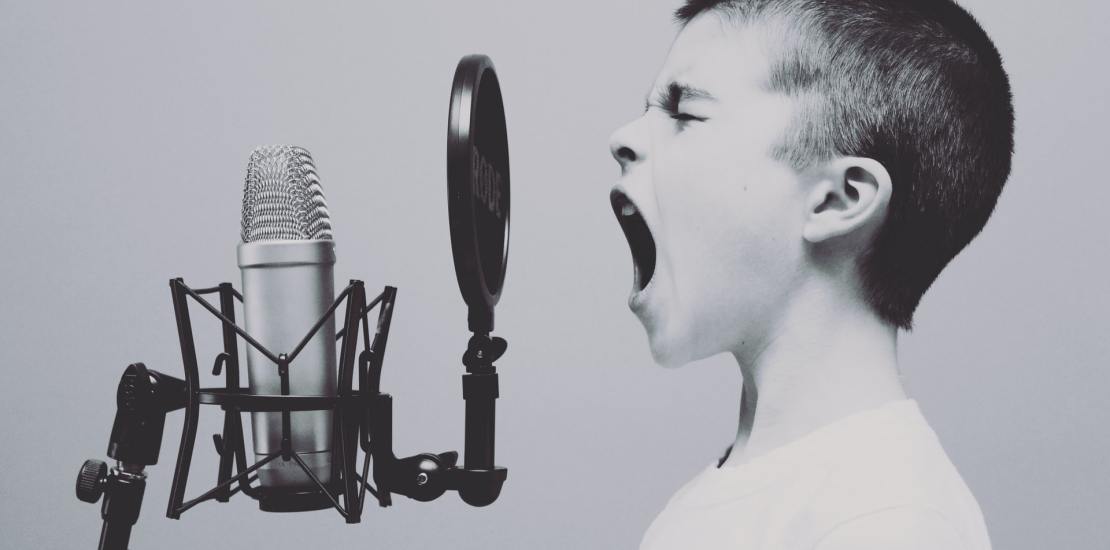 A kid singing with mouth wide open in front of a microphone